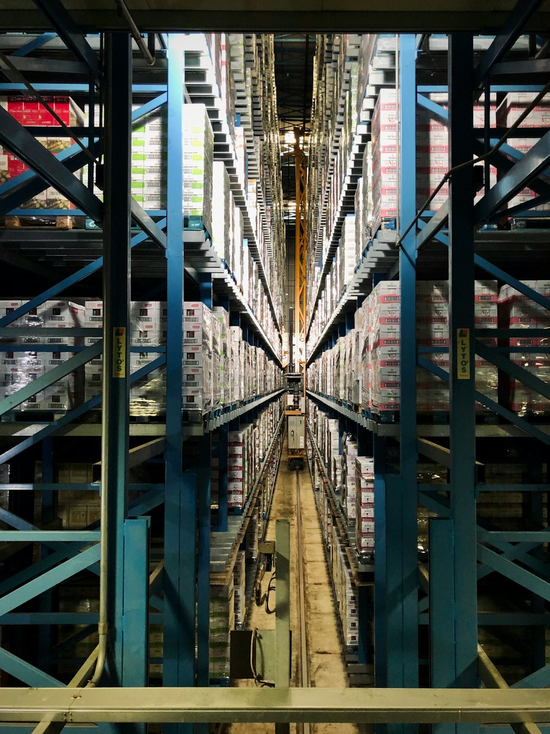 Automated warehouse aisle stacked with boxes and pallets.